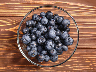 Bowl with tasty ripe bilberries on wooden background