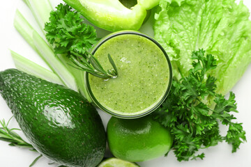 Glass of healthy green smoothie and vegetables on white background