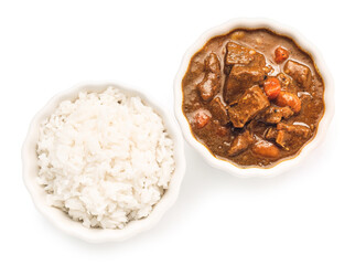 Bowls with tasty beef curry and rice on white background