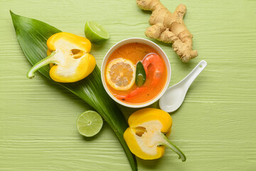 Bowl of spicy Thai soup on color wooden background