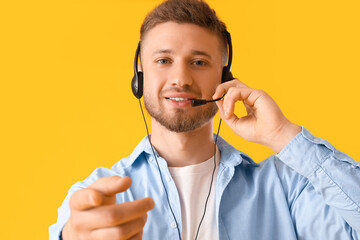 Handsome consultant of call center in headset on yellow background