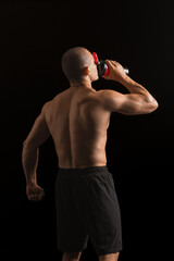 Fototapeta na wymiar Male bodybuilder drinking protein shake on dark background