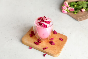 Glass of tasty rose latte on light background