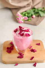 Glass of tasty rose latte on light background