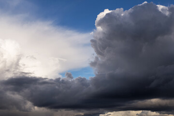 Epic dramatic Storm sky, dark grey and white cumulus clouds on blue sky background texture, thunderstorm. Darkness and light
