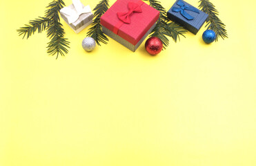 New Year's card with gifts, jewelry balls and fir branches. The yellow background is used so that you can write a message.