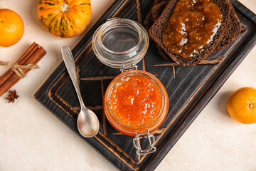 Jar of sweet pumpkin jam with oranges and toasts on white background