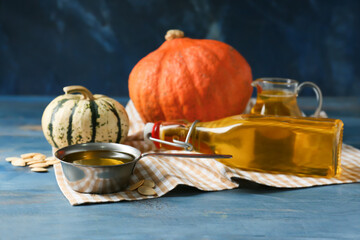 Bowl of pumpkin seed oil on color wooden background