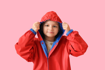 Little girl in stylish raincoat on color background