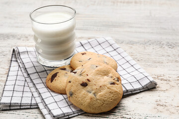 Tasty homemade cookies with chocolate chips and glass of milk on light wooden background