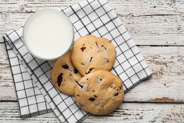 Tasty homemade cookies with chocolate chips and glass of milk on light wooden background