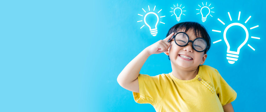 Smart kid nerd asian boy child with light bulb have good idea.Happy student kid thinking creative on blue banner background.Brainstorming and idea concept.online learning imagination innovation.stem.