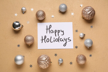 Text HAPPY HOLIDAYS and Christmas balls on beige background