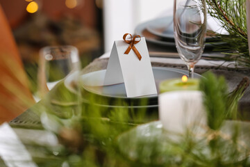 Dining table with beautiful setting for Christmas celebration with blank card indoors