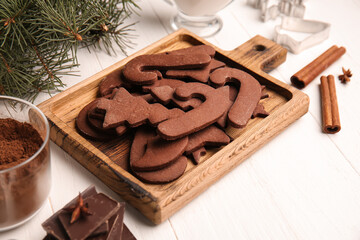 Board with tasty chocolate Christmas cookies and ingredients on white wooden background