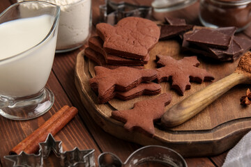 Board with tasty chocolate Christmas cookies on wooden background, closeup