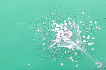 Glass with beautiful confetti on green background