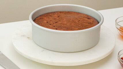 Fresh baked chocolate cake in baking pan, just from the oven, close up view on white kicthen table