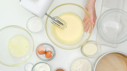 Woman hands mixing egg yolks with sugar in a glass bowl. Close up baking process