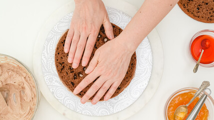 Obraz na płótnie Canvas Chocolate cake with cream and chocolate glaze step by step recipe. Woman hands assembling the cake, flat lay