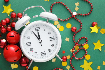 Stylish alarm clock and Christmas decor on green background