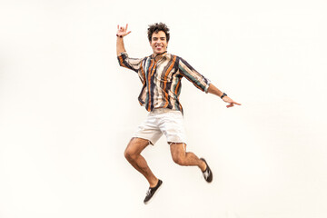 Fototapeta na wymiar Handsome spanish man jumping over white wall. Funny face. Happiness. Real people emotions.