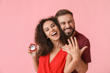 Happy young engaged couple on color background