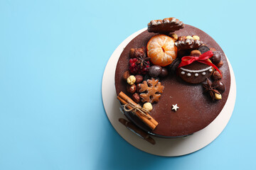 Stand with tasty Christmas chocolate cake on blue background