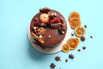 Stand with tasty Christmas chocolate cake and spices on blue background