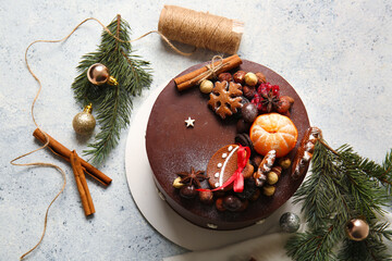 Composition with tasty Christmas chocolate cake and fir branches on light background