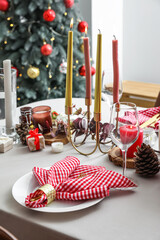 Beautiful Christmas table setting with burning candles in room