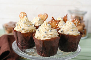 Stand with delicious Christmas cupcakes on table