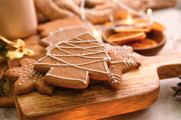 Wooden board with sweet Christmas gingerbread cookies on light background