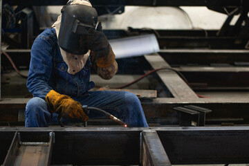 A worker welds steel in a factory with good protection.