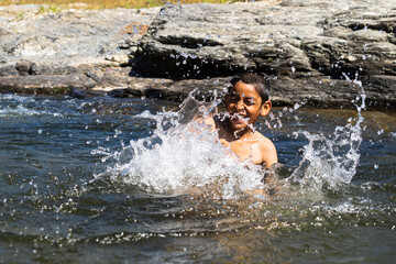 young village boy playing in the river full of water