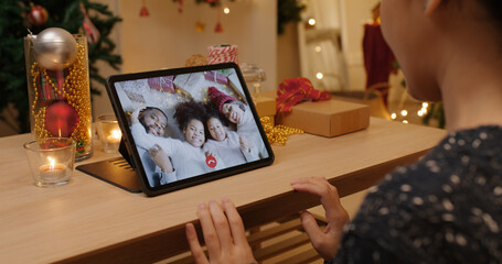 X'mas asia happy woman relax smile laugh greet in digital tablet screen remote talk to child kid friend at night online video VoIP party sit on cozy sofa at home enjoy good warm time winter season.