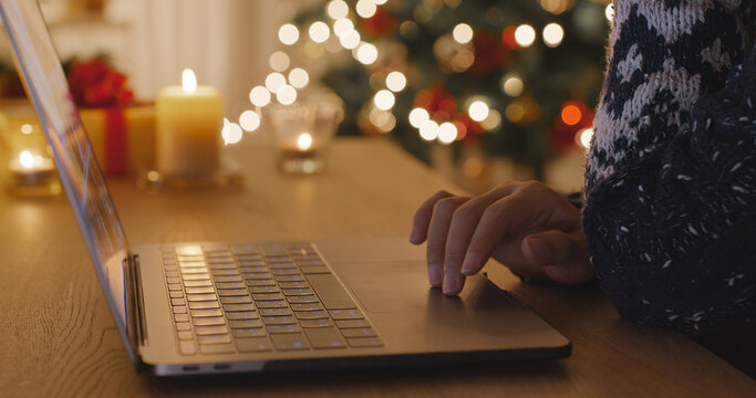 Close-up hand enter gift card on web page sending Merry Xmas eve wishing text on e-mail working on digital tablet laptop at home. Good warm time cozy night winter season with tree light inside house.