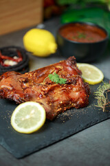 Homemade roast rat, Steak knife, fork, dipping sauce, steak knife, potato wedges close up on a slate board with dark gray color paint, old crumpled paper. Horizontal top view from above,grilled rats.