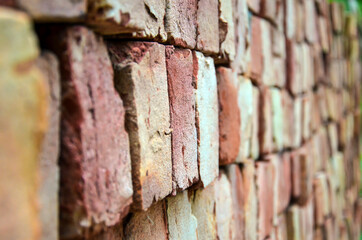 Stack of red bricks looks like brick wall. Selective focus on the pattern of bricks accumulated for the construction of a new building