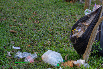 Garbage in black plastic bags that flooded strewn on the lawn in a tourist place.
