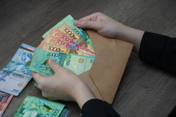 Almaty, Kazakhstan - 12.02.2021 : An envelope with money of different denominations of Kazakhstani tenge in the hands of a person