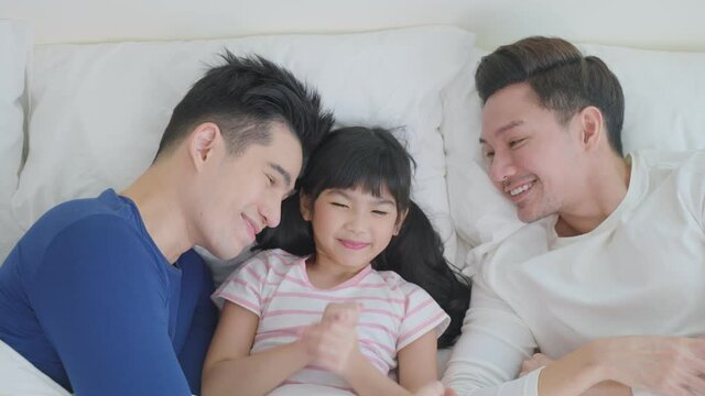 Portrait of handsome man gay family with young kid daughter in bedroom.	