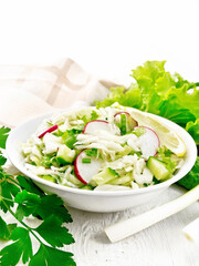 Salad of cabbage with radish in plate on wooden table