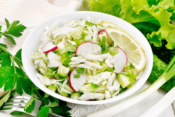 Salad of cabbage with radish in plate on wooden board