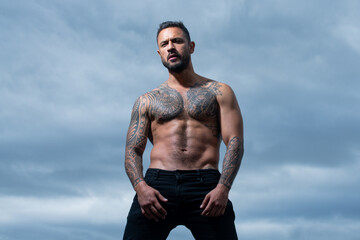 Brutal man, handsome serious male model. Tattooed and elegant hipster. Strong muscular male body,...