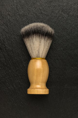 Stylish shaving brush with a wooden handle on a stone background. Flat lay.