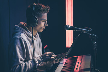 Young man in headphones behind the musical keys with a laptop.