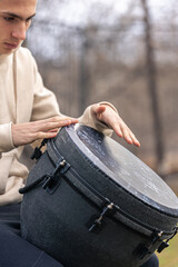 A man plays the djembe drum outside.