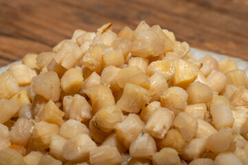 The plates or bowls in the wooden table contain scallops