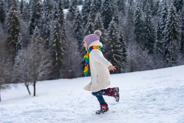 Fototapeta na wymiar Funny excited child girl running in snow on winter outdoor. Children in winter outdoor in frost snowy day.